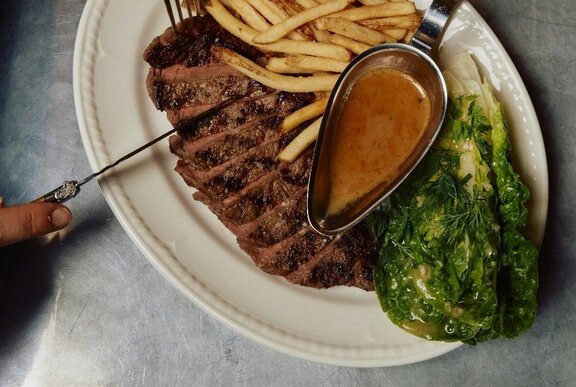 Top down view of a steak frites plate, with slice steak, fries and a salad.