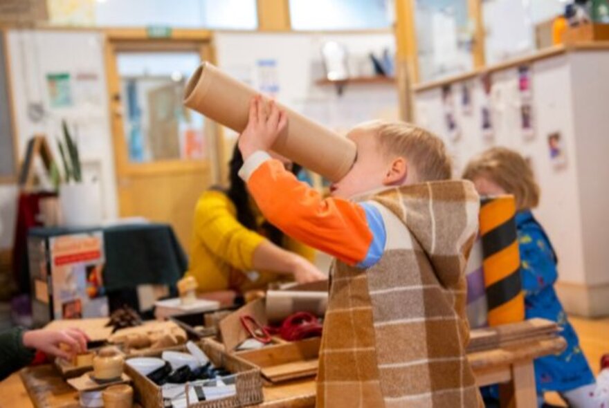 Young children at a craft table engaged in an activity.