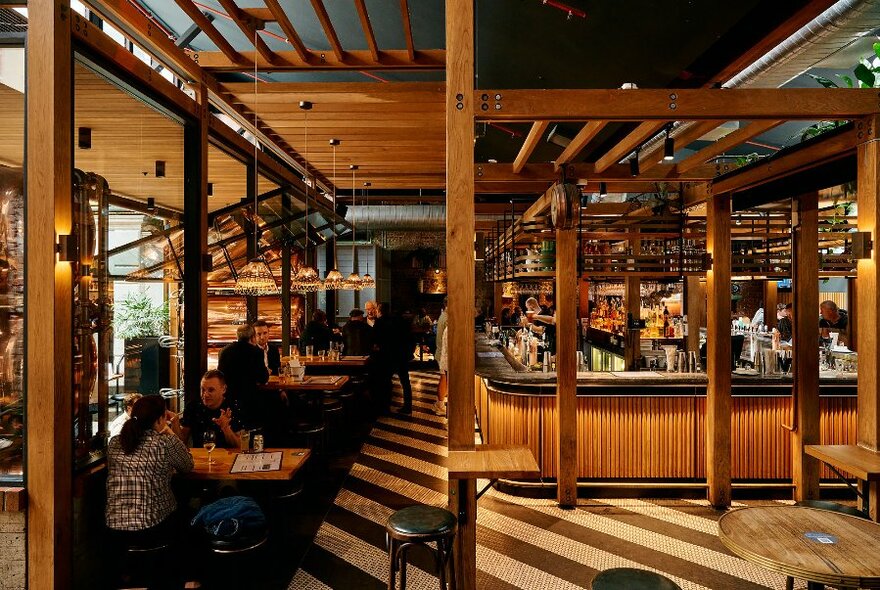 Bar interior, with horizontal and vertical wooden beams throughout, and tables to the left. 