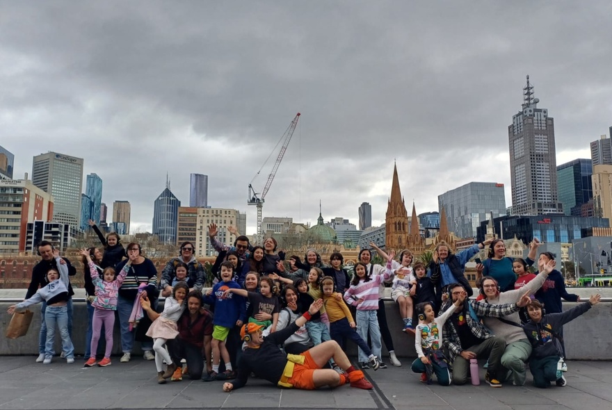Flash mob tour group gathered on a rooftop with Melbourne buildings and storm clouds in the background.