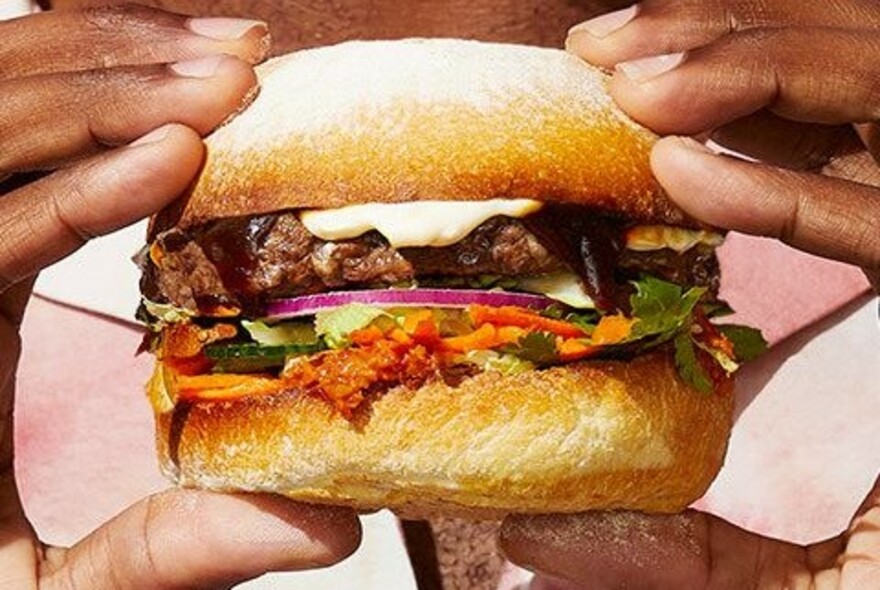 Hands holding a juicy burger.