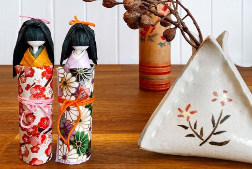 Traditional Japanese paper and wooden dolls displayed on a table.