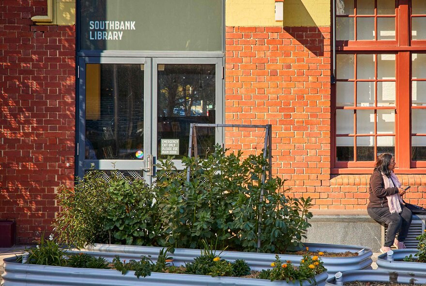 Exterior of Southbank Library and Boyd Community Hub, a brick building featuring large windows and an outdoor seating area with planter boxes.