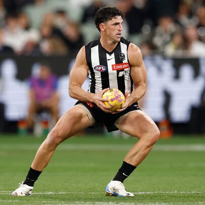A Collingwood AFL football player on the field with the ball during a match.