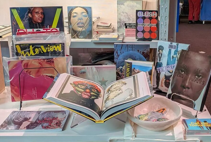 A display table with fashion magazines and books arranged for an exhibition.
