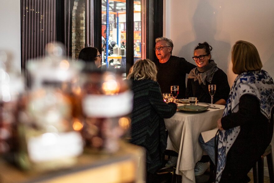 People seated at a dining table and eating in a spacious room.