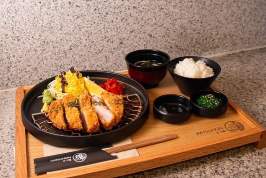 A plate of Katsu don with rice and condiments.