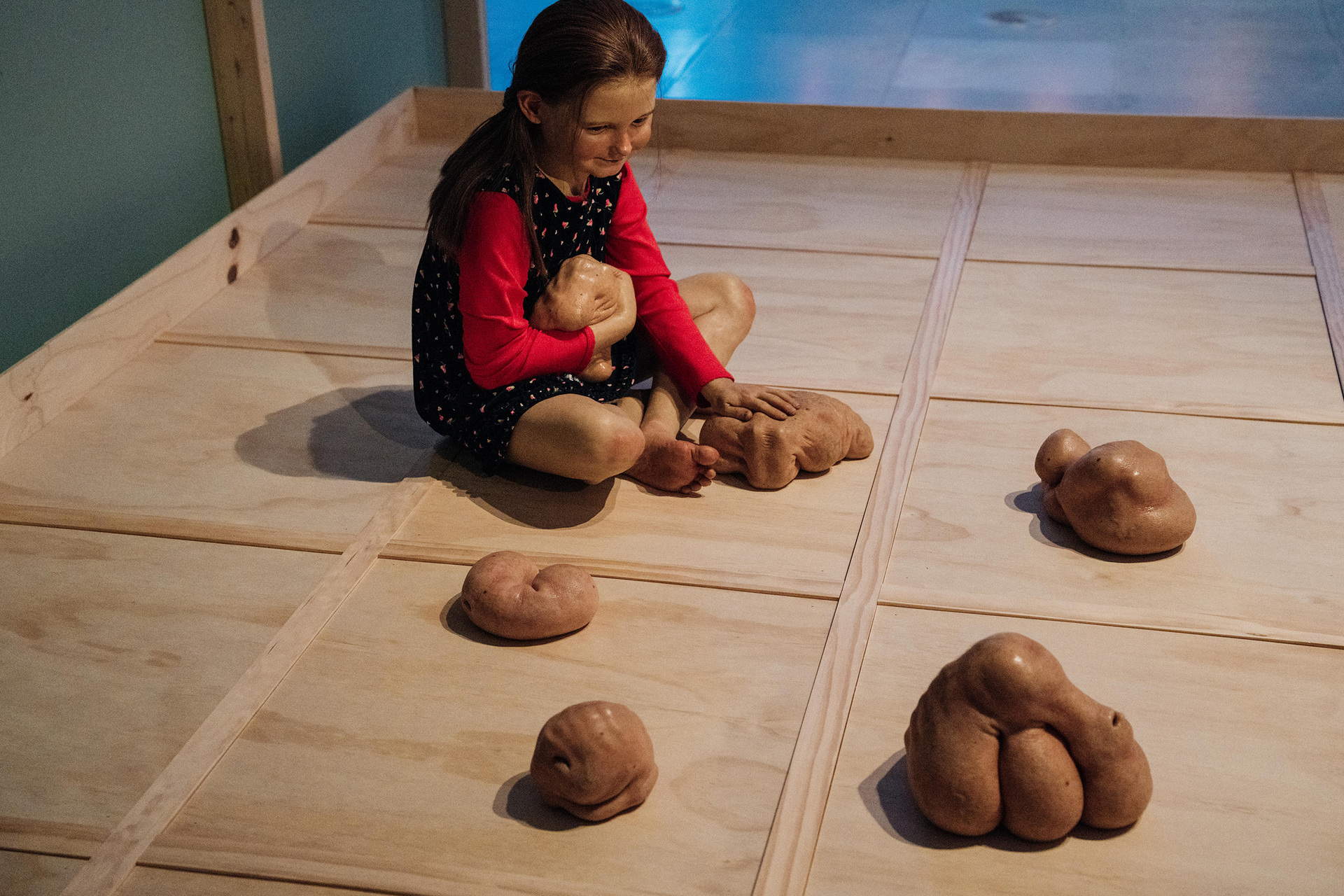 A realistic statue of a young person playing with fleshy blobs