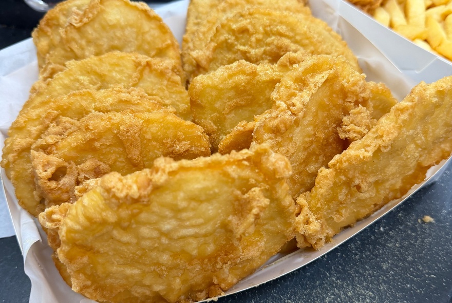 A tray of fish and chip shop style potato cakes.