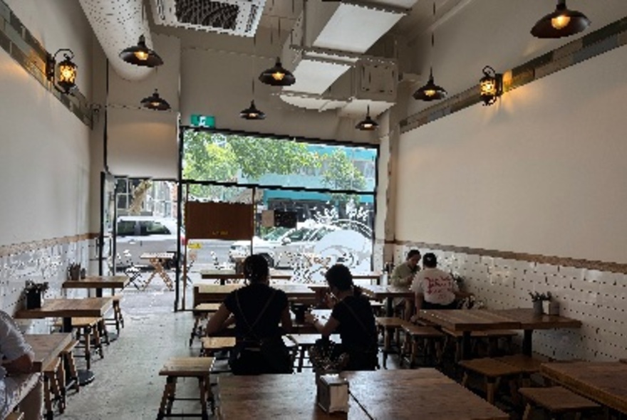 The interior of a small restaurant looking towards the main window to the street. 