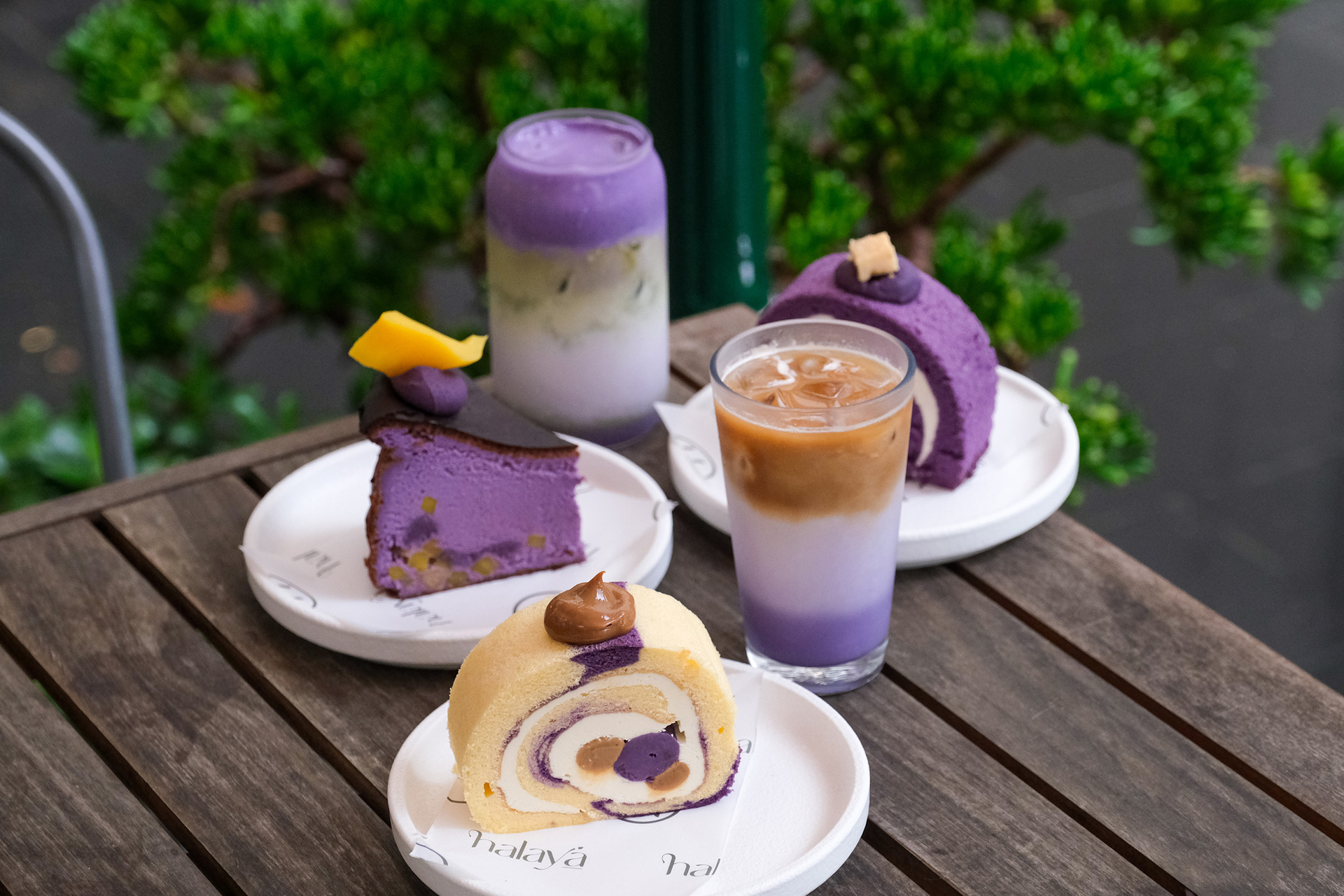 A table with plates of ube cakes and ube drinks on it