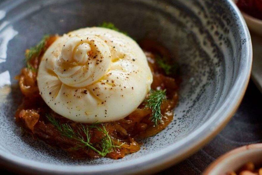 A ball of cheese on a bed of caramelised fruit.