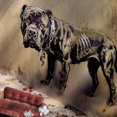 Stencil painting of a large, skeletal black dog on a wall, with a miniature worn red sofa in the foreground.