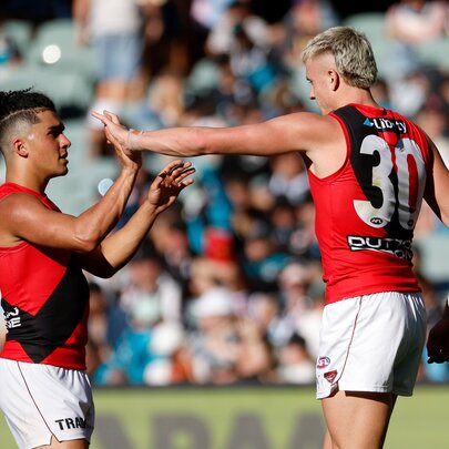 Essendon AFL football players on the field during a match giving each other a high five.