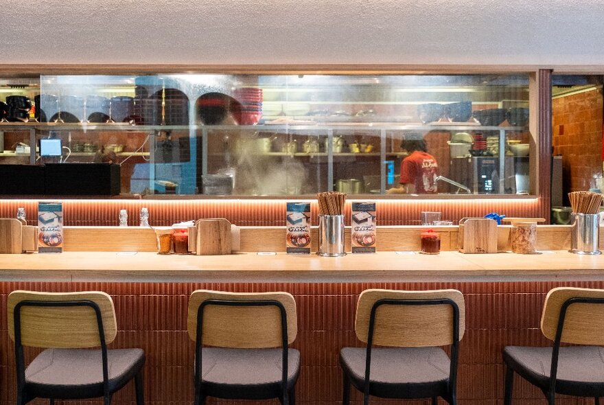 Bar seats lined up at a long counter in a Japanese restaurant.