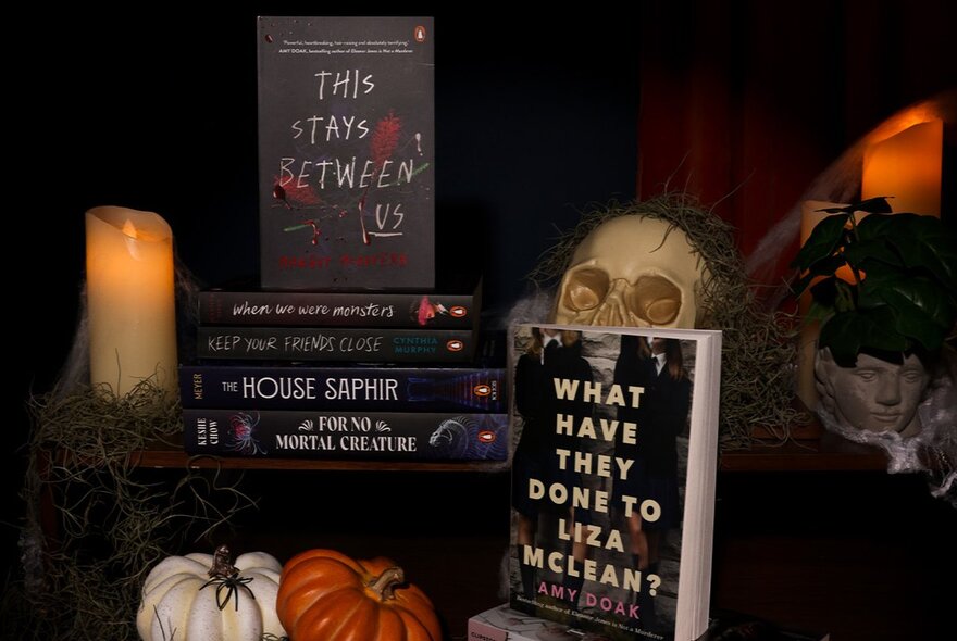 A collection of young adult horror-themed books, presented amidst skulls, candles and Halloween pumpkins.
