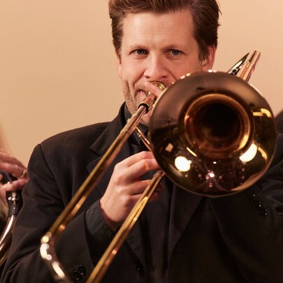 Classical musicians performing with shiny brass instruments.