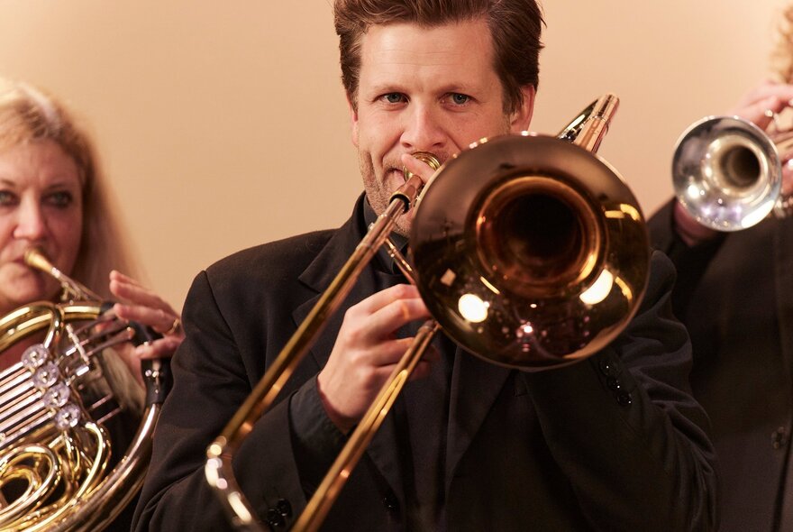 Classical musicians performing with shiny brass instruments.