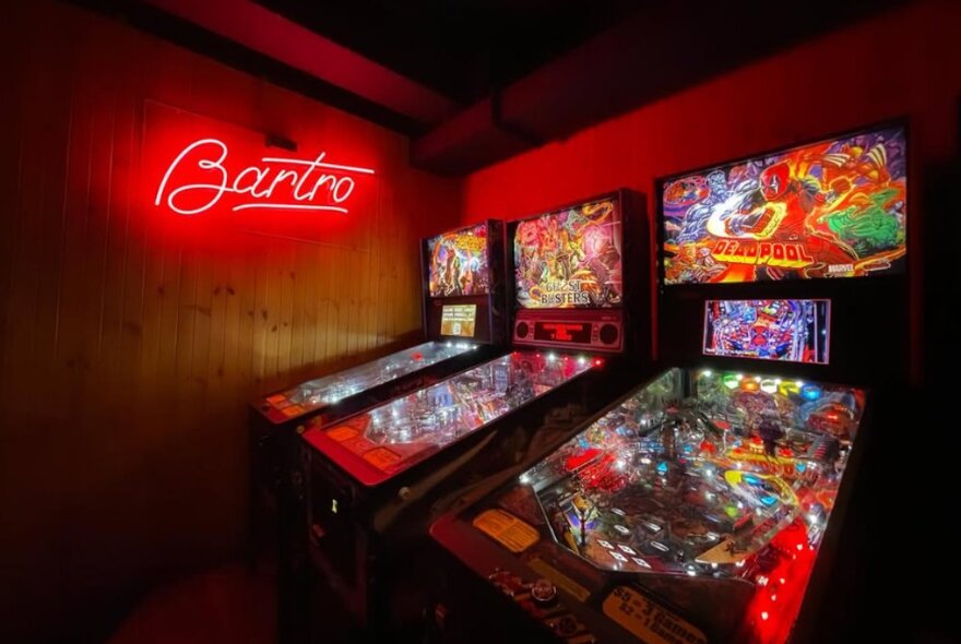 Three arcade games next to a sign that reads 'Bartro'.