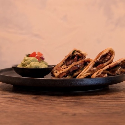 A dish of Mexican tacos with a bowl of guacamole.