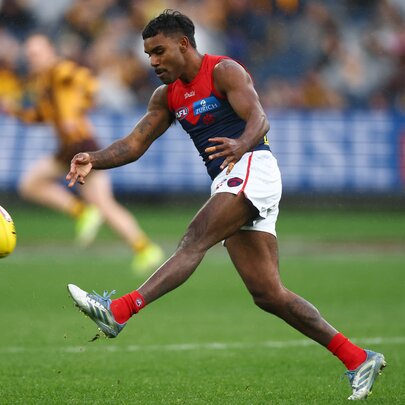 Melbourne AFL football player kicking the ball on the field during a match.