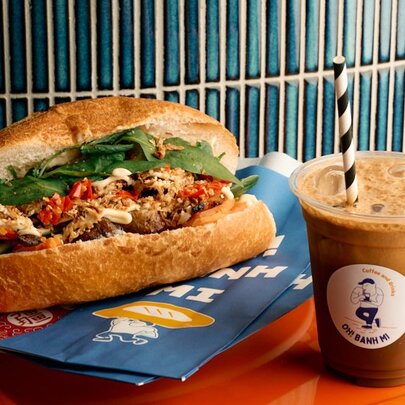 Vietnamese banh mi roll with an iced coffee with straw.