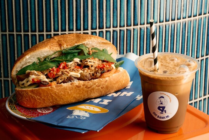 Vietnamese banh mi roll with an iced coffee with straw.