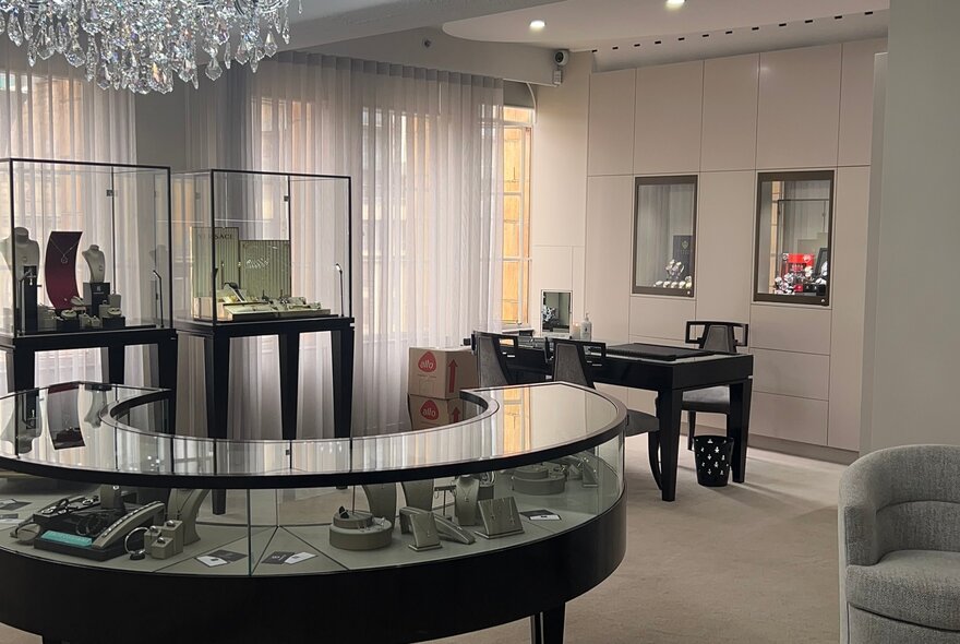 The carpeted interior showroom of Franco Jewellers with glass display cabinets, and a desk with two club chairs for buyers to sit at.
