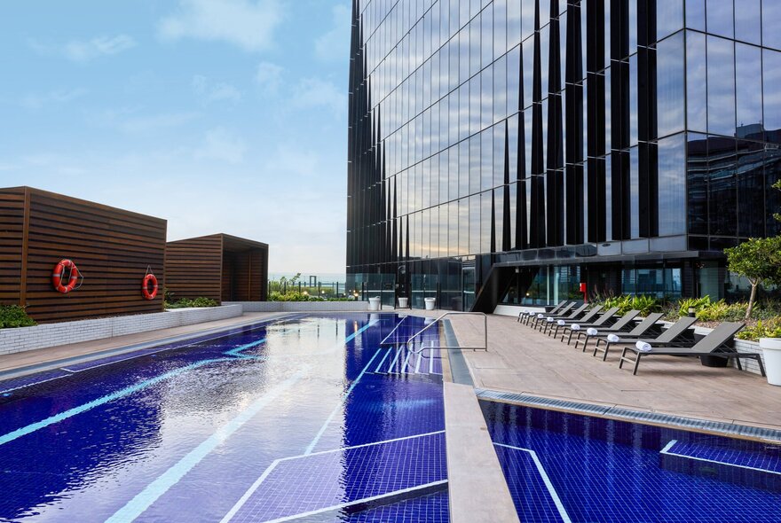 Hotel elevated pool and seating area with high-rise floors in background.