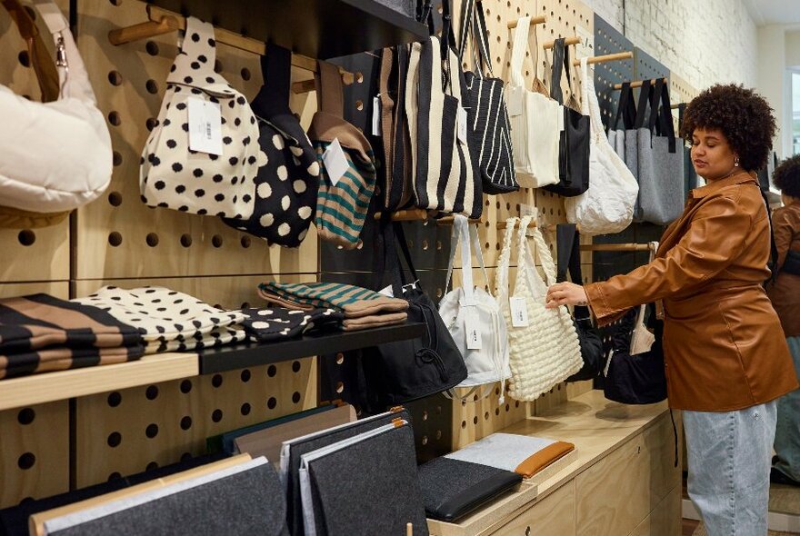 A woman is looking at bags in a store