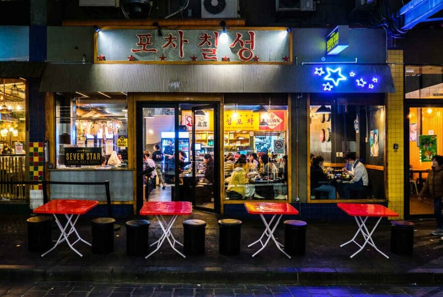 Red tables lined up outside a small restaurant in a laneway.