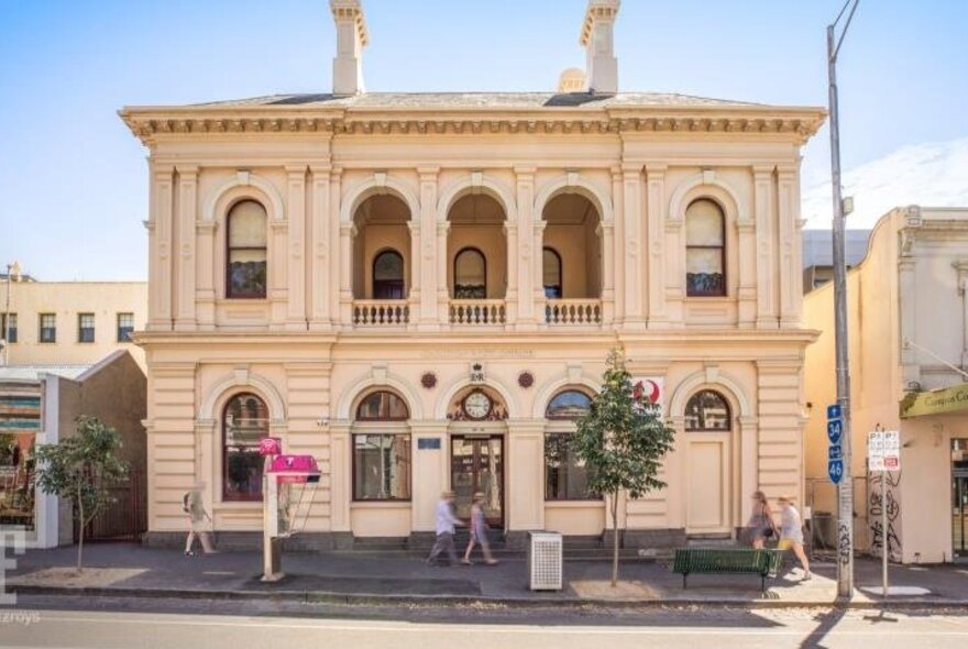 Large heritage building with arcaded first-floor and arched windows and doors on ground-floor level.