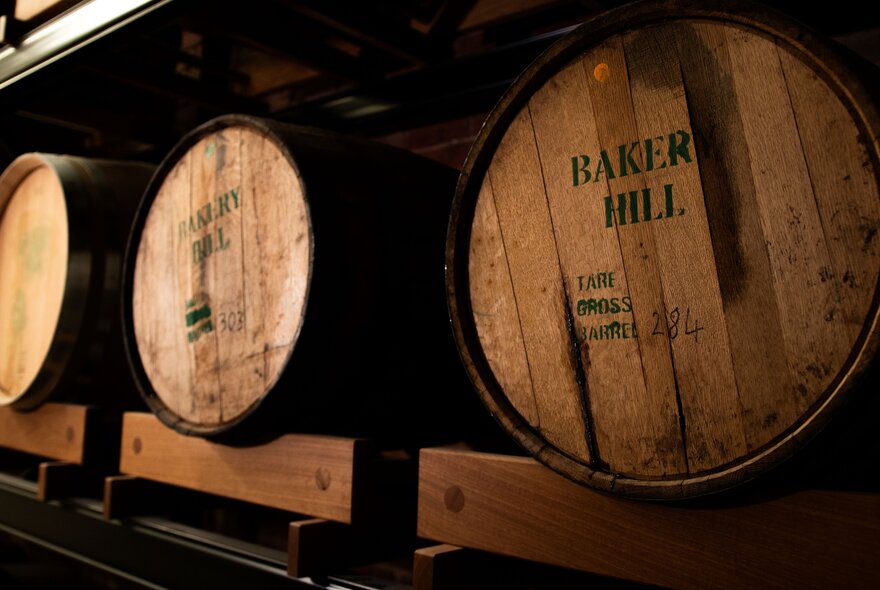 Large oak barrels resting on racks inside the Bakery Hill whisky distillery.