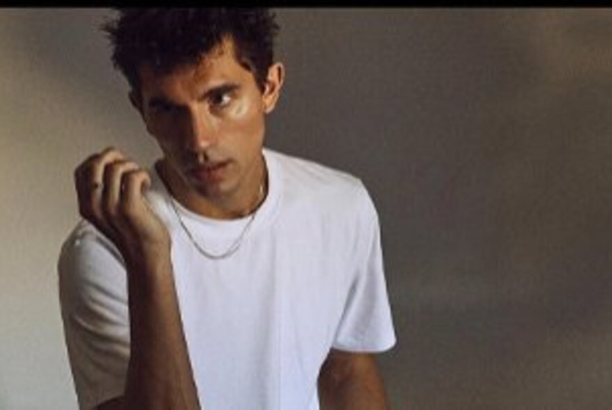 Man wearing a white T-shirt and necklace.
