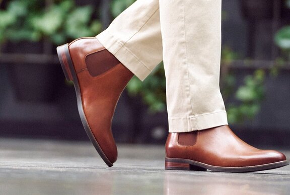 Feet modelling a pair of brown leather men's boots.