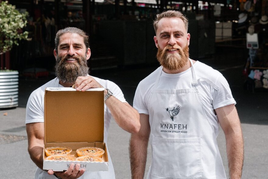 Two bearded men, one holding a box of desserts.