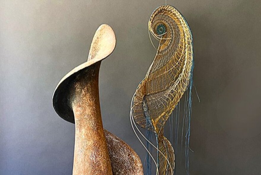 Sculptural artworks against a taupe coloured wall.