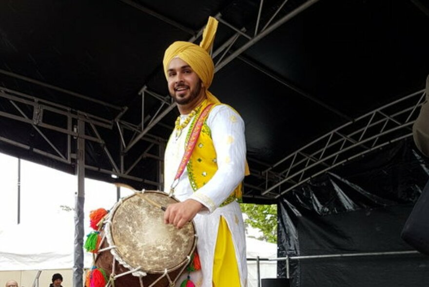 A traditionally dressed Indian drummer wearing a kurta and turban.