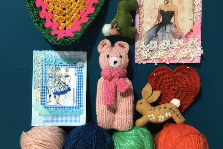 A selection of small hand-crafted crafts such as a pink knitted bear, a felt rabbit, crocheted hearts.