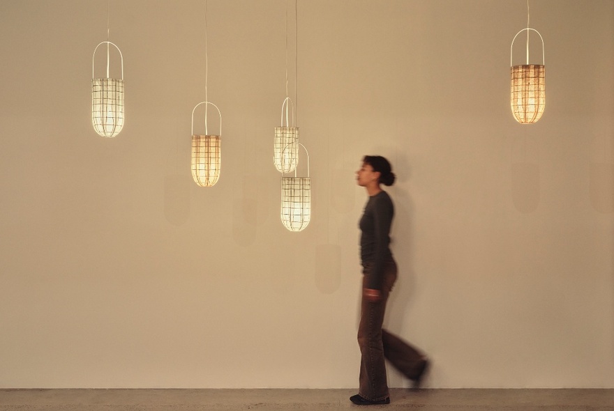 A person walking past a display of illuminated paper sculpture lanterns.