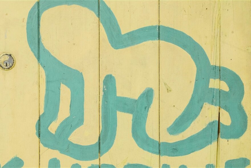 Keith Haring wall mural of a crawling baby, blue paint on yellow boards.