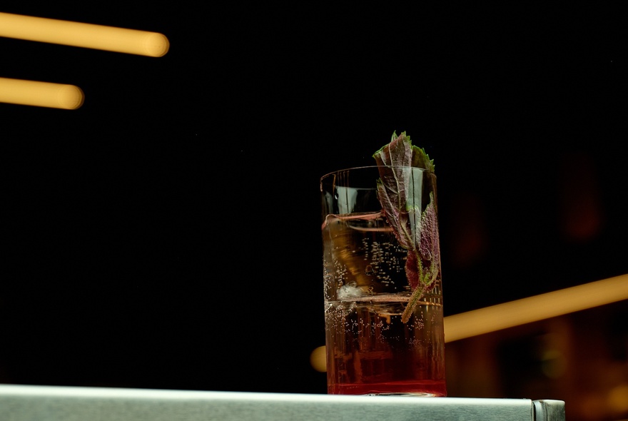 Chopsticks hovering near a whisky highball.