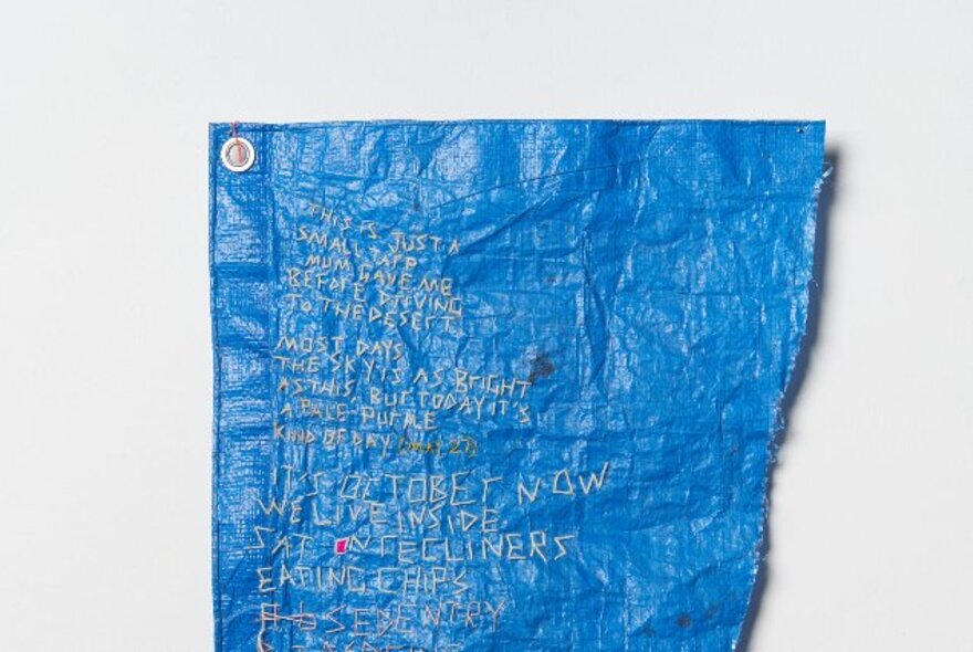 Blue textile artwork with embroidered words.