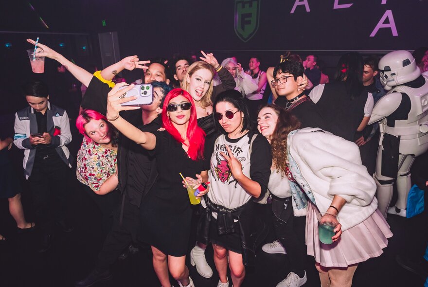 Crowd of young people taking selfies in a dark venue.