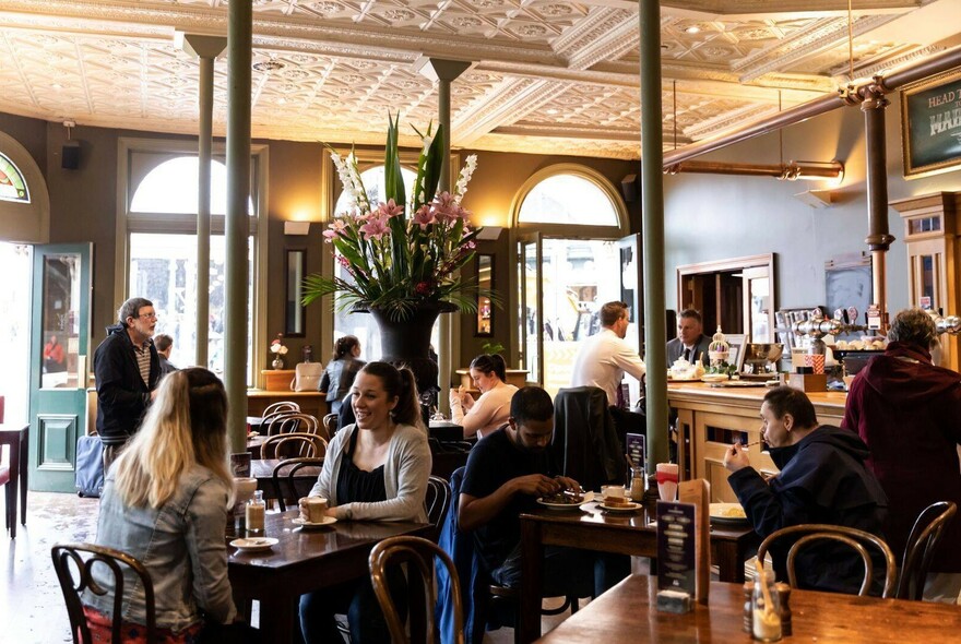 Interior of Young & Jackson Hotel with bar in background, and patrons drinking and dining at tables.