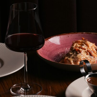Plates of food and a glass of red wine on a table.
