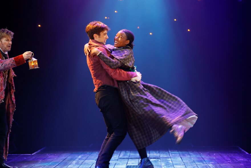 A couple dancing on stage, wearing period costume.