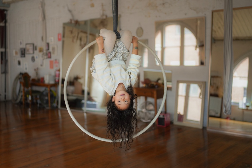 Child suspended upside-down from an aerial swing.