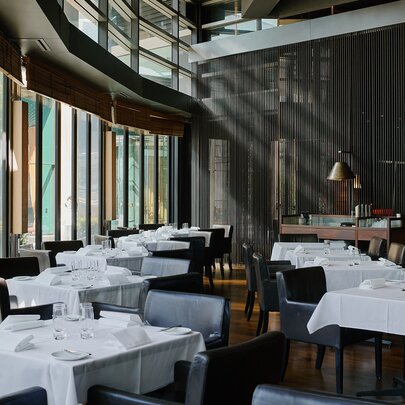 Interior of Rockpool Bar & Grill restaurant showing dining tables covered in white linen and set for a meal service.