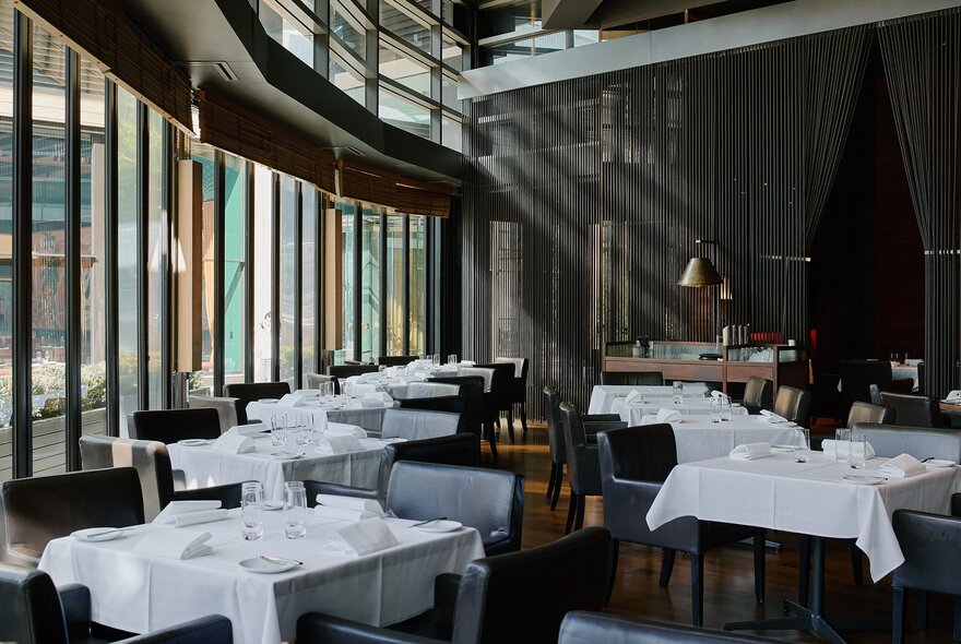 Interior of Rockpool Bar & Grill restaurant showing dining tables covered in white linen and set for a meal service.